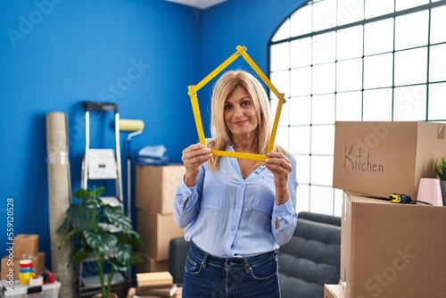 Middle age blonde woman moving to a new home relaxed with serious expression on face. simple and natural looking at the camera. photo