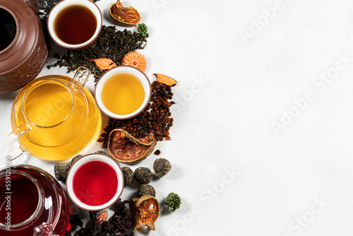 A set of tea black, green, red in a teapot with cups and loose. Top view on light background with copy space.