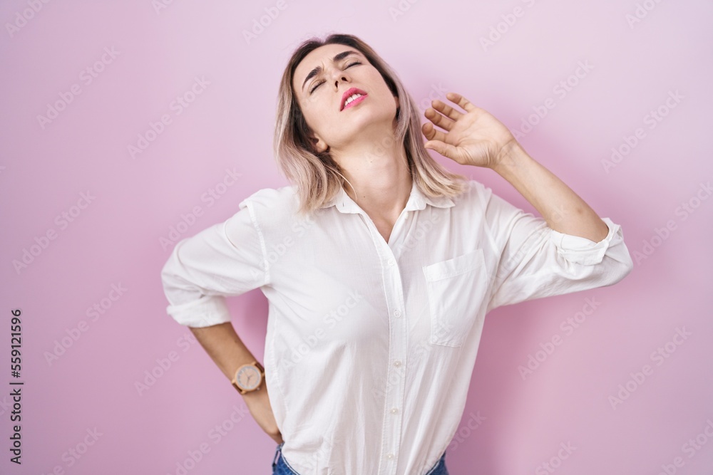 Young beautiful woman standing over pink background stretching back, tired and relaxed, sleepy and yawning for early morning Young beautiful woman standing over pink background stretching back, tired and relaxed, sleepy and yawning for early morning