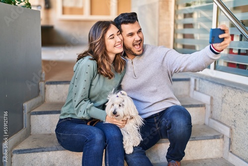 Man and woman holding dog making selfie by the smartphone at street