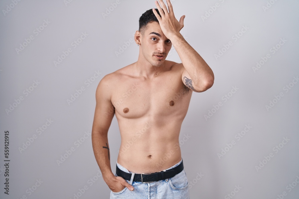 Handsome hispanic man standing shirtless surprised with hand on head for mistake, remember error. forgot, bad memory concept.