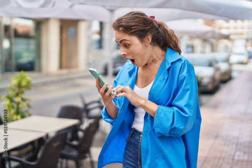 Fototapeta premium Young woman using smartphone with cheerful expression at street