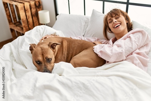 Young caucasian woman smiling confident lying on bed with dog at bedroom © Krakenimages.com