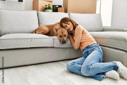 Young caucasian woman relaxed with hands on head sitting on floor with dog at home