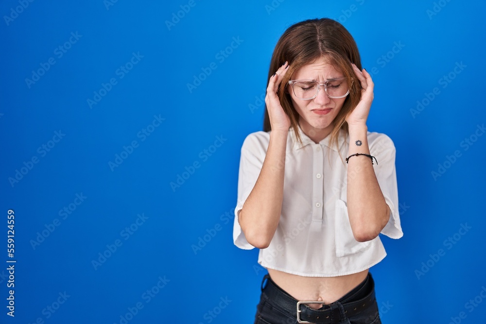Beautiful woman standing over blue background with hand on head for pain in head because stress. suffering migraine. Beautiful woman standing over blue background with hand on head for pain in head because stress. suffering migraine.