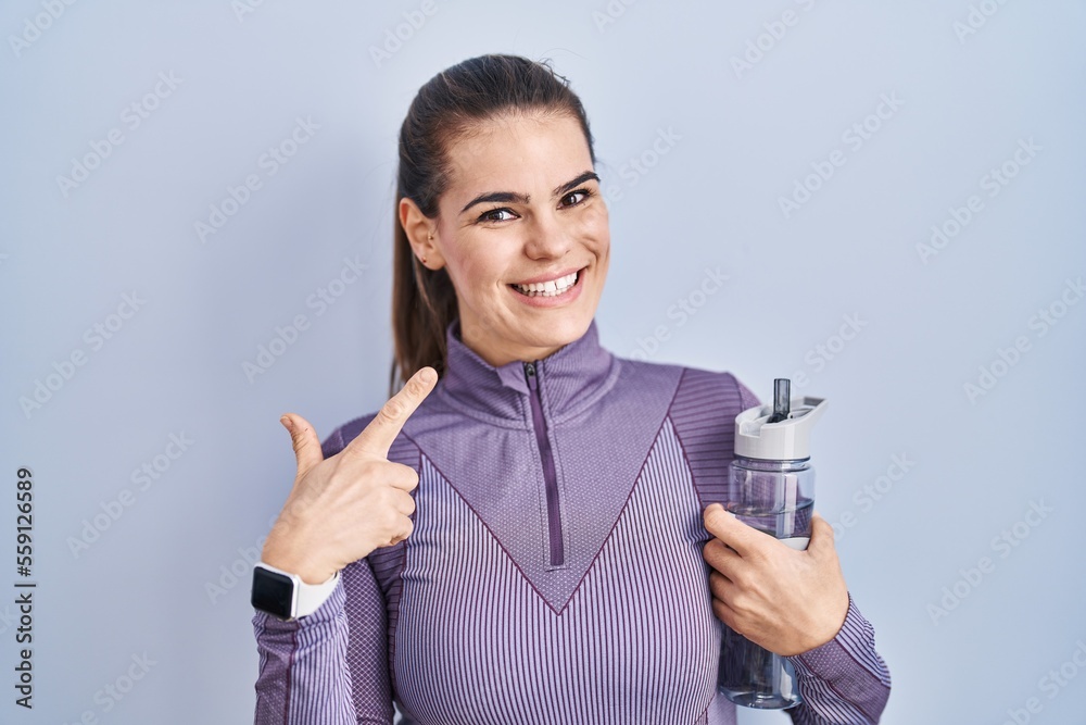 Beautiful woman wearing sportswear holding water bottle smiling cheerful showing and pointing with fingers teeth and mouth. dental health concept. Beautiful woman wearing sportswear holding water bottle smiling cheerful showing and pointing with fingers teeth and mouth. dental health concept.