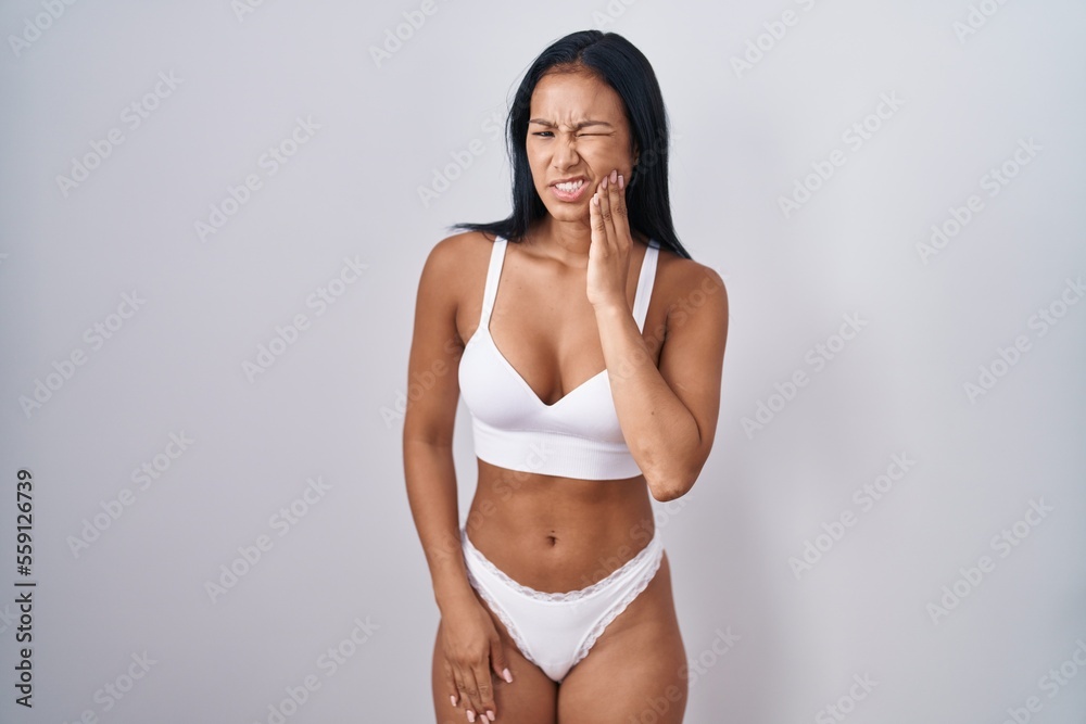 Hispanic woman wearing lingerie touching mouth with hand with painful expression because of toothache or dental illness on teeth. dentist Hispanic woman wearing lingerie touching mouth with hand with painful expression because of toothache or dental illness on teeth. dentist