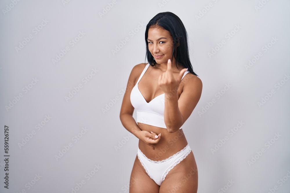 Fototapeta premium Hispanic woman wearing lingerie beckoning come here gesture with hand inviting welcoming happy and smiling