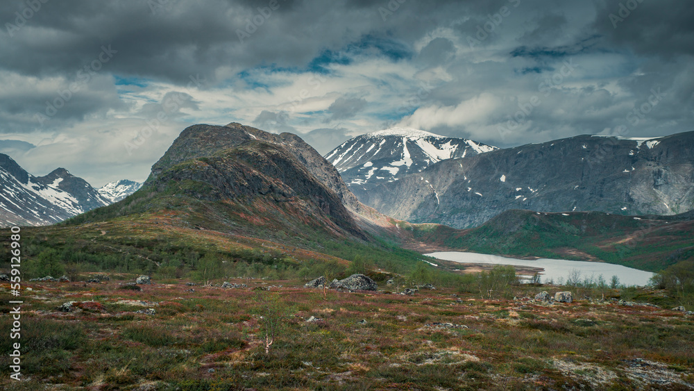 Mountain landscape with hike to Knutshoe summit in Jotunheimen National Park in Norway, snow covered mountains of Besseggen in background
