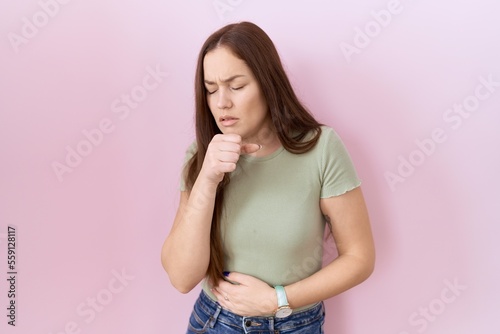 Beautiful brunette woman standing over pink background feeling unwell and coughing as symptom for cold or bronchitis. health care concept.