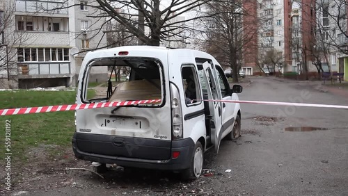 Chernihiv, Ukraine - April 17, 2022:Enclosing red-white signal tape area with damaged car after an artillery attack by Russia troops. Damaged car after the attack by Russian aircraft.