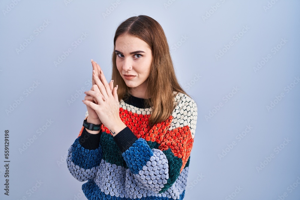 Young hispanic girl standing over blue background holding symbolic gun with hand gesture, playing killing shooting weapons, angry face Young hispanic girl standing over blue background holding symbolic gun with hand gesture, playing killing shooting weapons, angry face
