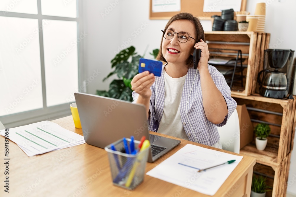 Middle age hispanic woman businesswoman making payment on the phone at business office Middle age hispanic woman businesswoman making payment on the phone at business office