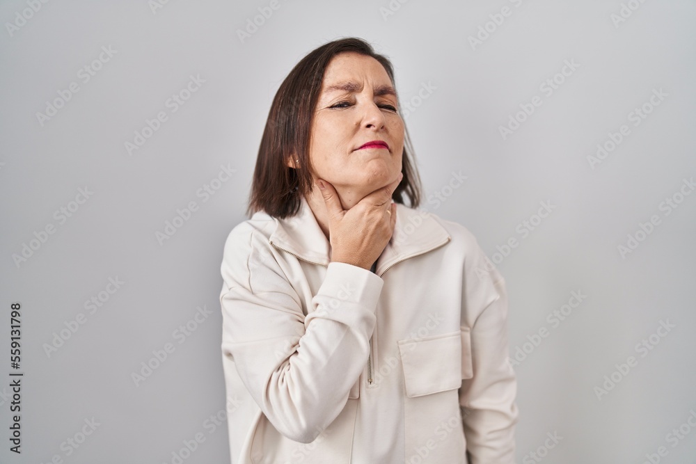 Middle age hispanic woman standing over isolated background touching painful neck, sore throat for flu, clod and infection Middle age hispanic woman standing over isolated background touching painful neck, sore throat for flu, clod and infection