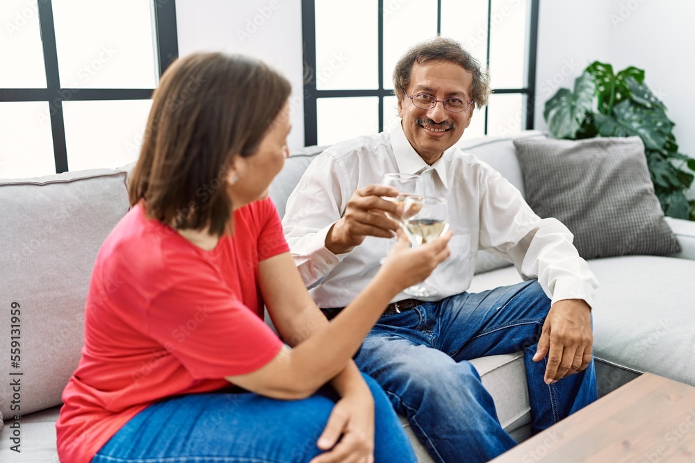 Obraz premium Middle age man and woman couple smiling confident toasting with champagne at home