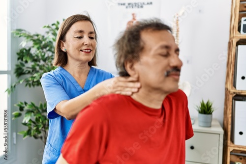 Middle age man and woman wearing physiotherapy uniform having rehab session massaging neck at physiotherapy clinic © Krakenimages.com