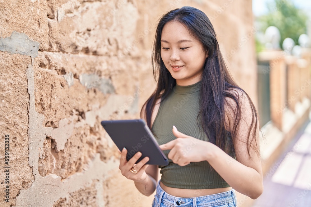 Young chinese woman smiling confident using touchpad at street Young chinese woman smiling confident using touchpad at street
