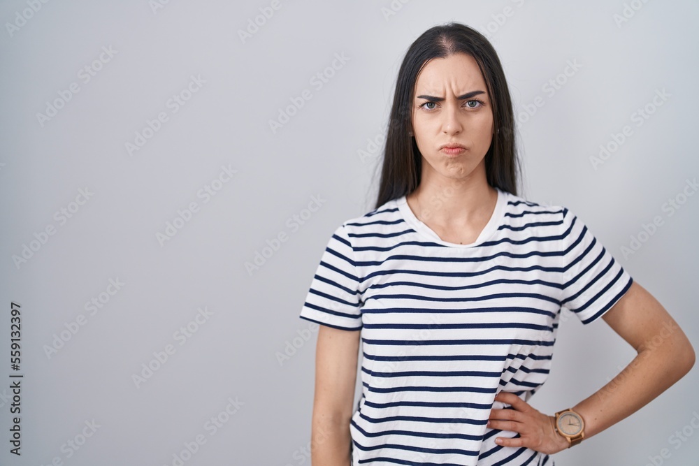 Young brunette woman wearing striped t shirt skeptic and nervous, frowning upset because of problem. negative person. Young brunette woman wearing striped t shirt skeptic and nervous, frowning upset because of problem. negative person.