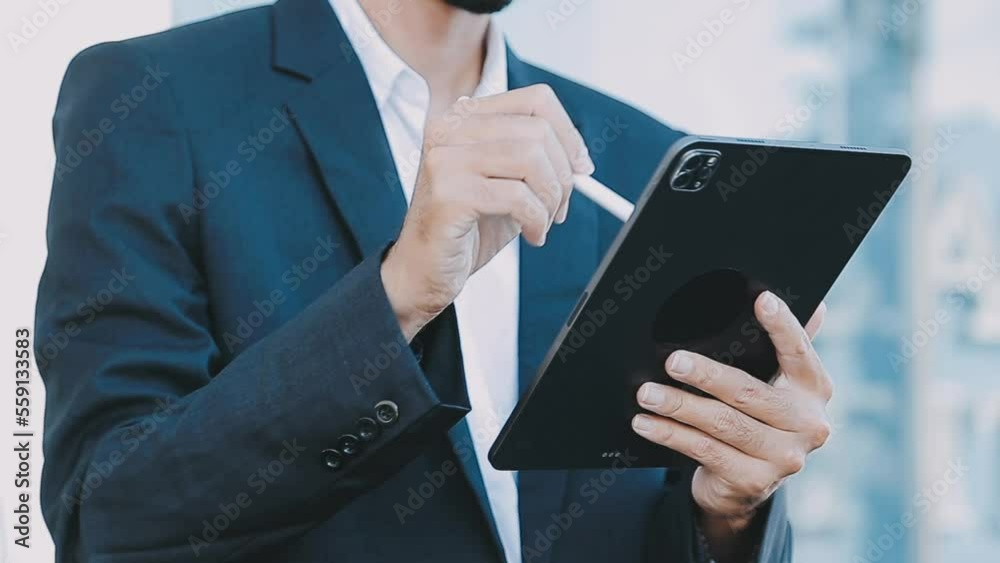 Mature businessman using a digital tablet to discuss information with a younger colleague in a modern business lounge Mature businessman using a digital tablet to discuss information with a younger colleague in a modern business lounge