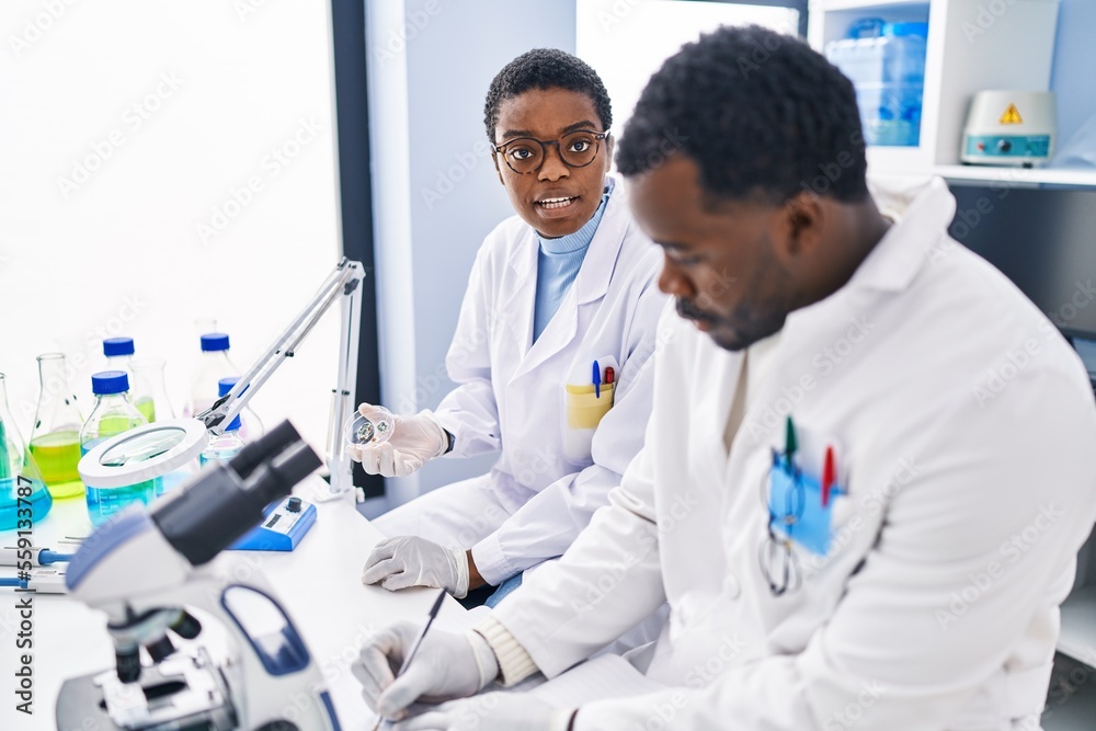Man and woman scientists writing on notebook working at laboratory Man and woman scientists writing on notebook working at laboratory