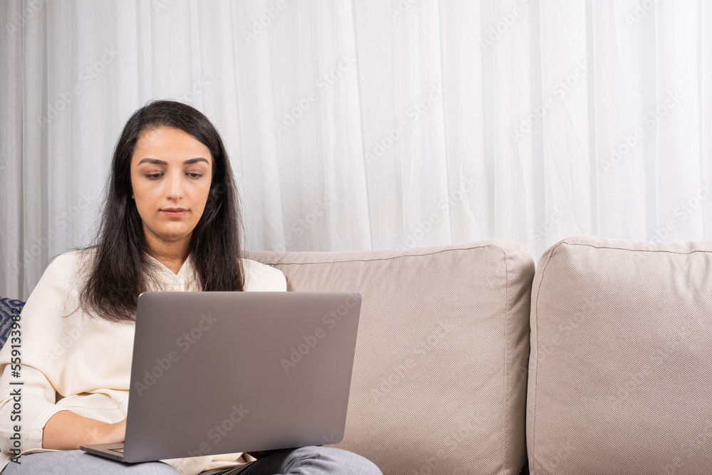 Woman using laptop, freelancer millennial woman using laptop. Serious girl working on computer at home sitting sofa, writing email, attending online meeting, watching webinar, studying concept idea. Woman using laptop, freelancer millennial woman using laptop. Serious girl working on computer at home sitting sofa, writing email, attending online meeting, watching webinar, studying concept idea.