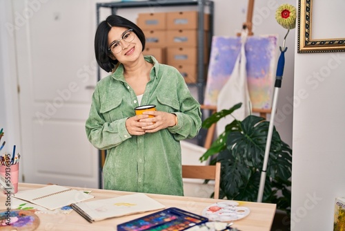 Young chinese woman artist smiling confident drinking coffee at art studio