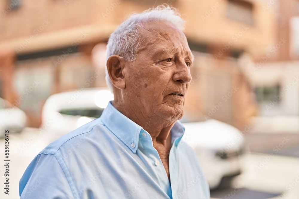 Senior grey-haired man with relaxed expression standing at street Senior grey-haired man with relaxed expression standing at street