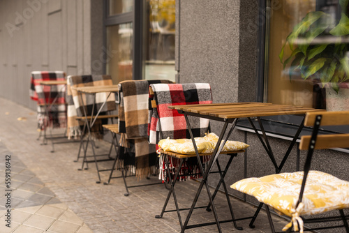 Table and chairs with blanket outdoors in street cafe on grey cement floor background. Lifestyle, leisure, drinking, eating out concept, romantic