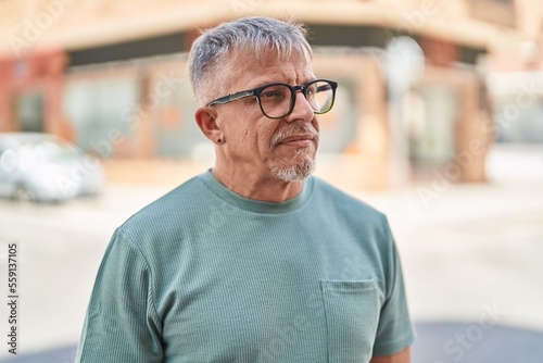 Middle age grey-haired man standing with serious expression at street
