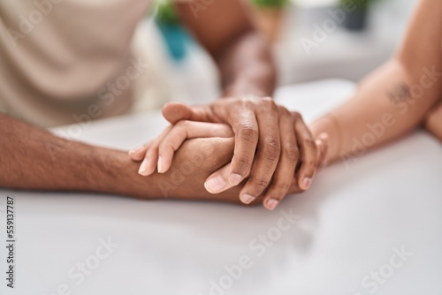 Man and woman couple sitting on table with hands together at home