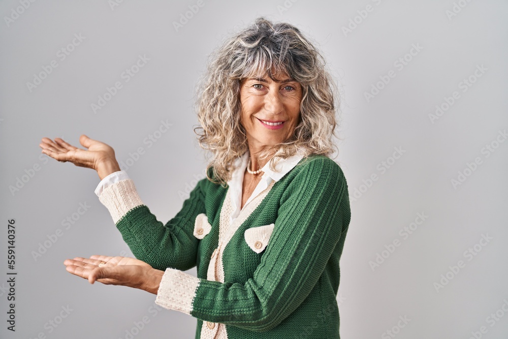 Middle age woman standing over white background inviting to enter smiling natural with open hand Middle age woman standing over white background inviting to enter smiling natural with open hand