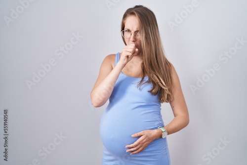 Young pregnant woman standing over white background feeling unwell and coughing as symptom for cold or bronchitis. health care concept.