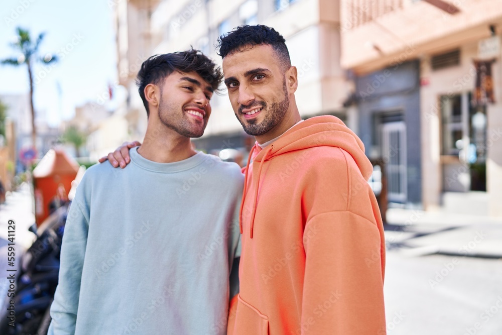 Two man couple hugging each other standing at street