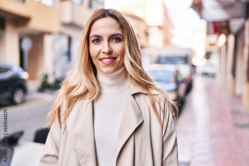 Young blonde woman smiling confident standing at street