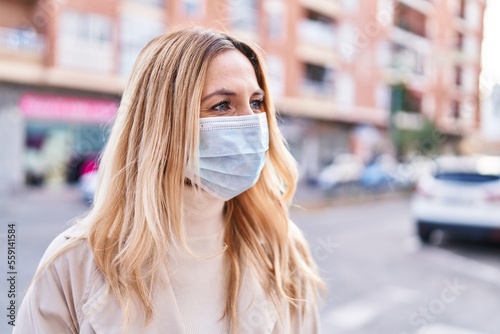 Young blonde woman wearing medical mask standing at street
