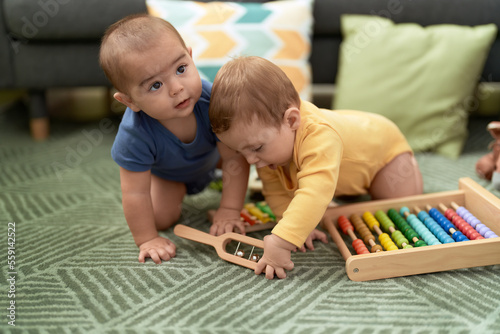 Two toddlers playing with abacus sitting on floor at home