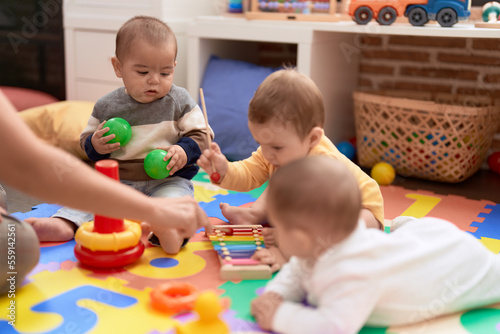 Group of toddlers playing with toys sitting on floor at kindergarten