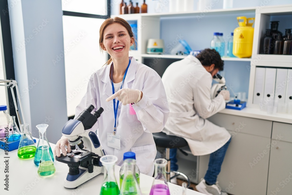 Young two people working at scientist laboratory smiling happy pointing with hand and finger Young two people working at scientist laboratory smiling happy pointing with hand and finger