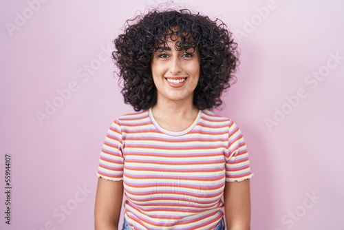 Young middle east woman standing over pink background with a happy and cool smile on face. lucky person. © Krakenimages.com