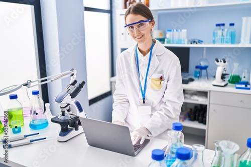 Young caucasian woman scientist smiling confident using laptop at laboratory