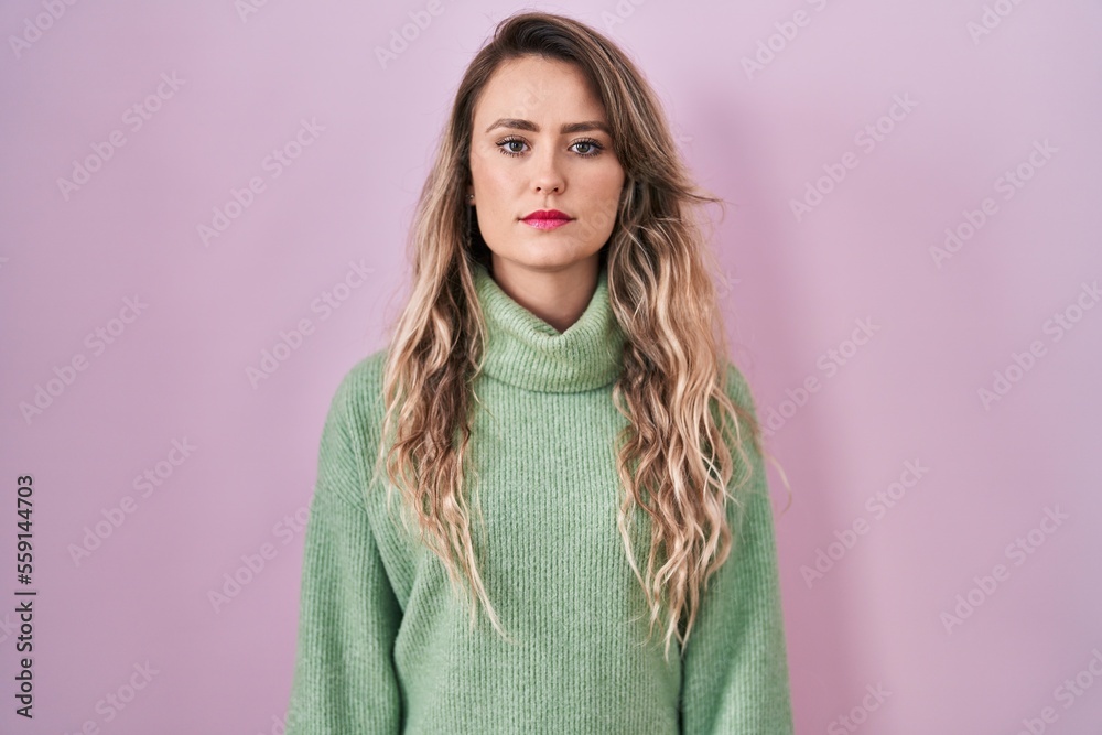 Young caucasian woman standing over pink background relaxed with serious expression on face. simple and natural looking at the camera. Young caucasian woman standing over pink background relaxed with serious expression on face. simple and natural looking at the camera.