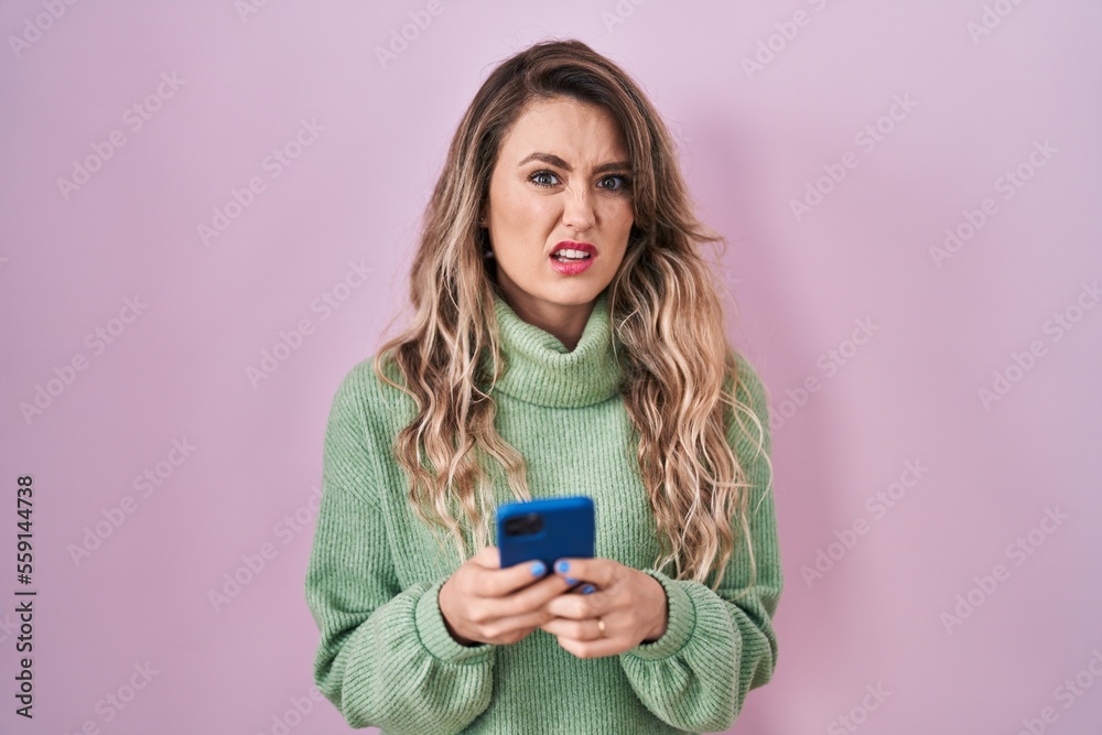 Young caucasian woman using smartphone typing message clueless and confused expression. doubt concept. Young caucasian woman using smartphone typing message clueless and confused expression. doubt concept.