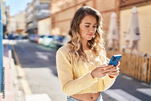 Young woman using smartphone with relaxed expression at street