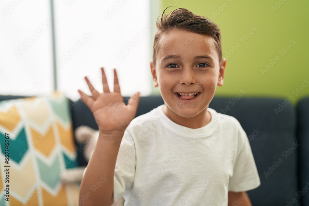 Adorable hispanic toddler smiling confident saying hello with hand at home Adorable hispanic toddler smiling confident saying hello with hand at home
