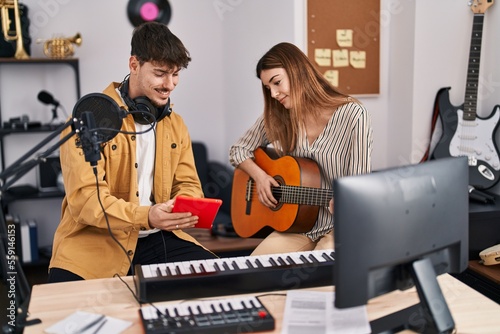 Mand and woman musicians playing classical guitar using touchpad at music studio