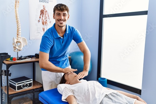 Man and woman wearing physiotherpy uniform having reiki therapy session at clinic