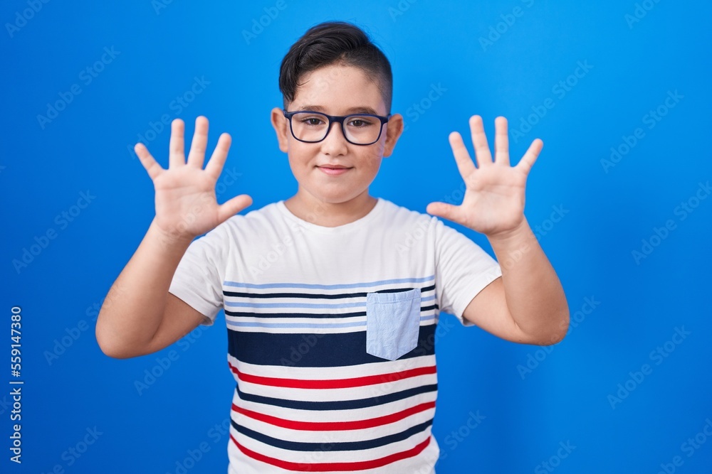 Young hispanic kid standing over blue background showing and pointing up with fingers number ten while smiling confident and happy. Young hispanic kid standing over blue background showing and pointing up with fingers number ten while smiling confident and happy.