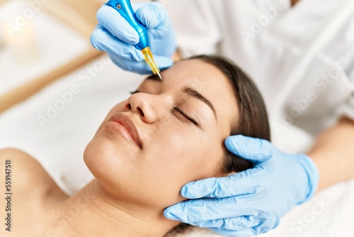 Young latin woman relaxed having microblading eyebrows treatment at beauty center