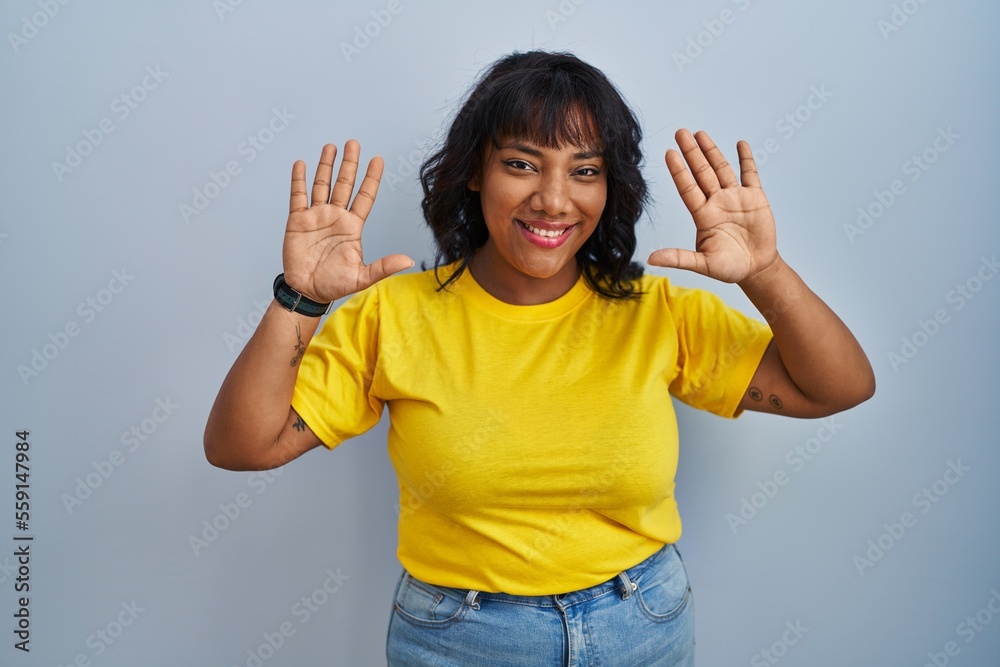 Hispanic woman standing over blue background showing and pointing up with fingers number ten while smiling confident and happy. Hispanic woman standing over blue background showing and pointing up with fingers number ten while smiling confident and happy.