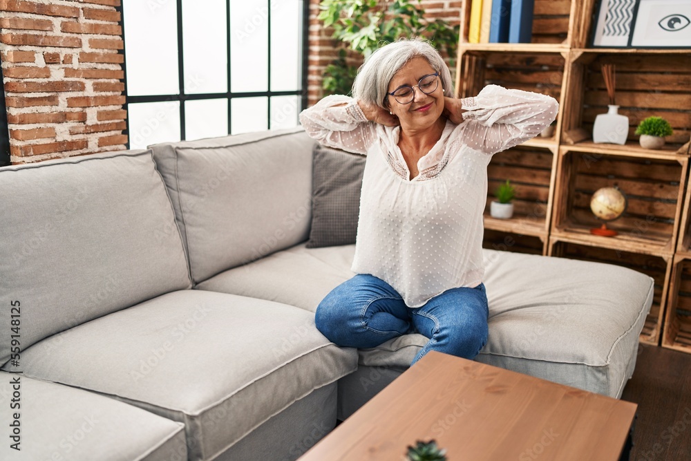 Middle age woman sitting on sofa suffering for neck pain at home Middle age woman sitting on sofa suffering for neck pain at home
